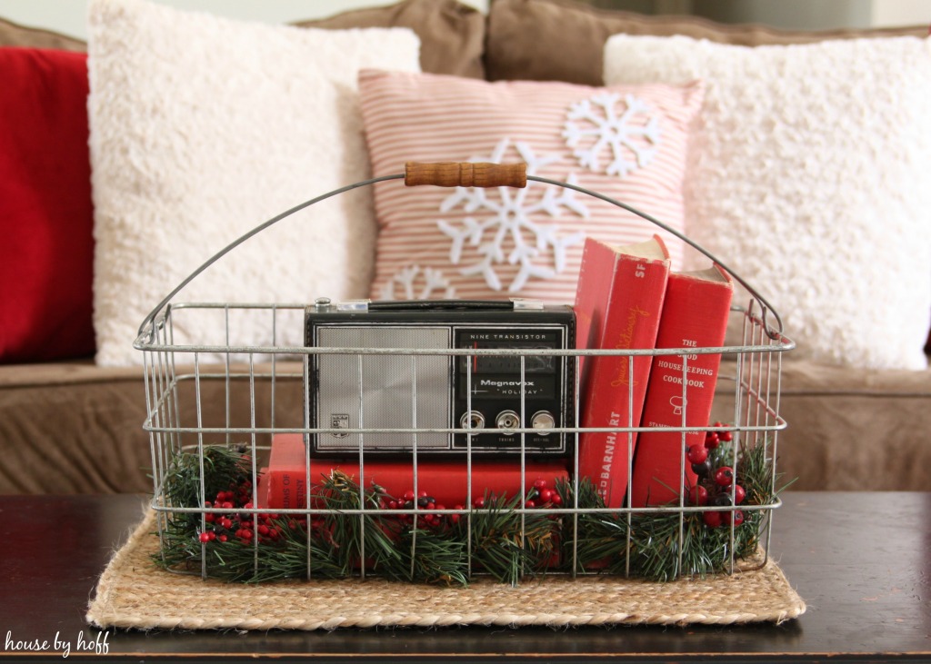 A wire basket with a small vintage radio, old books and holly.