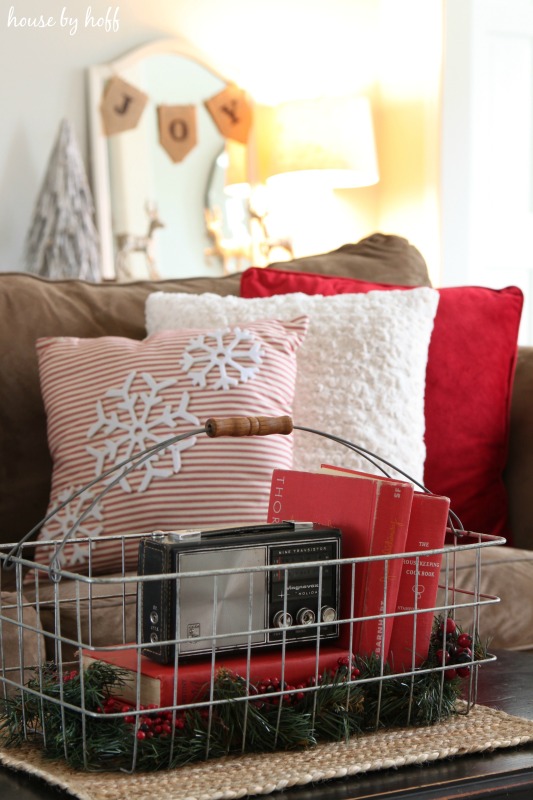 A wire basket with books and holly on the coffee table.