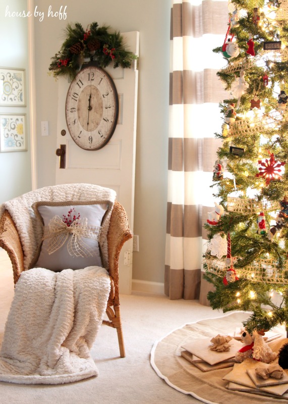 A pillow with a neutral burlap bow and a sprig of red berries beside the Christmas tree.