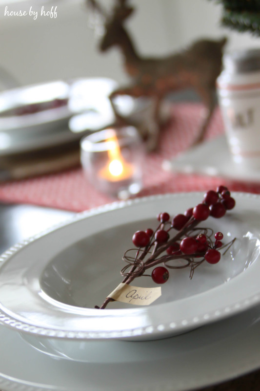 A little sprig of red berries is on the white plates with a small tag and guests name written on it.