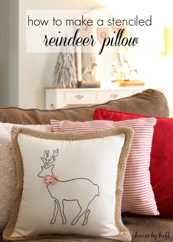 Adorable reindeer pillow in white with a stencilled reindeer on it on the couch.