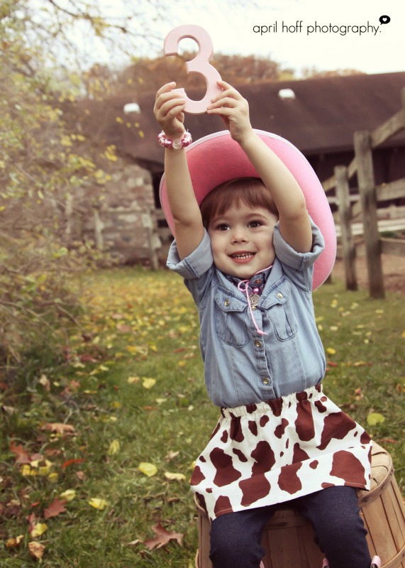 Girl in her pink cowboy hat holding a number 3.