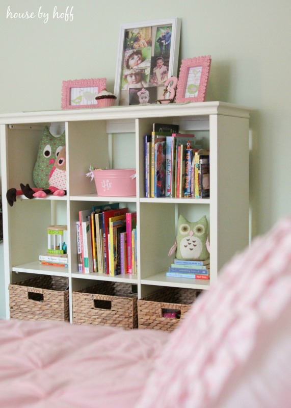 White bookshelf with framed pictures on it and books on the shelf.