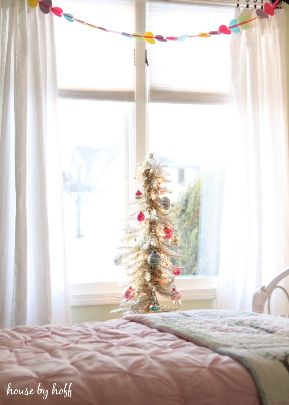 A multi colored garland in the window above the the Christmas tree.