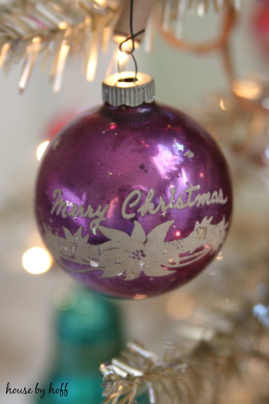 A purple ornament that says Merry Christmas is on the tree.