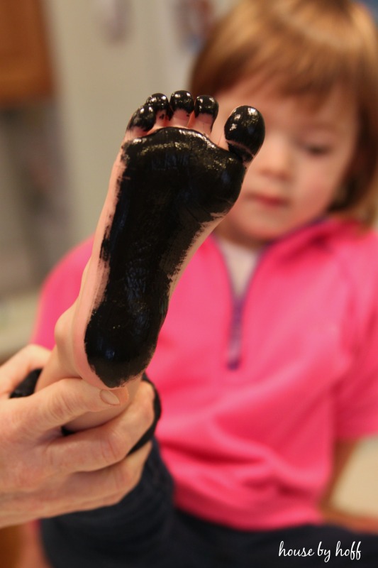 Black paint on child's foot held up by a hand.