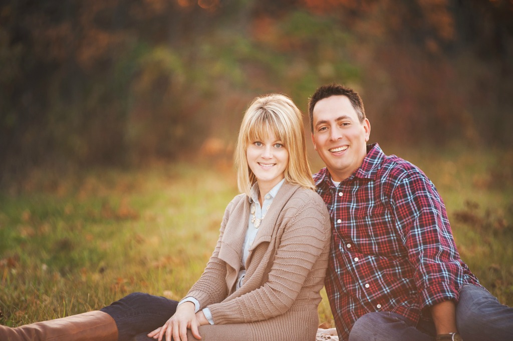 Husband and wife portrait picture sitting in the grass.