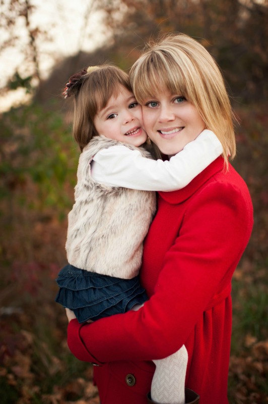 A blonde Mom holding her daughter with her arms wrapped around Mom's neck.