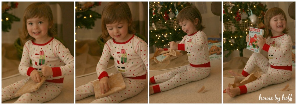 A little girl opening up a Christmas book with delight.