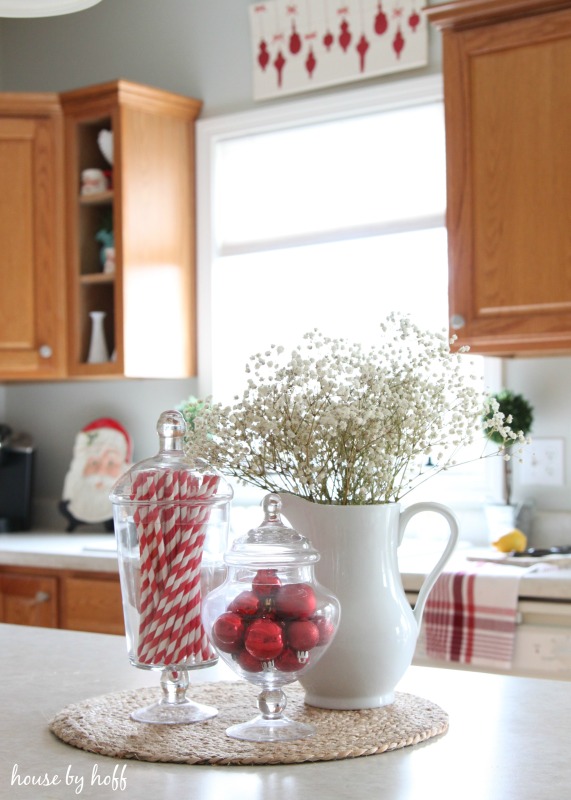There is a jar filled with candy canes on the island in the kitchen.