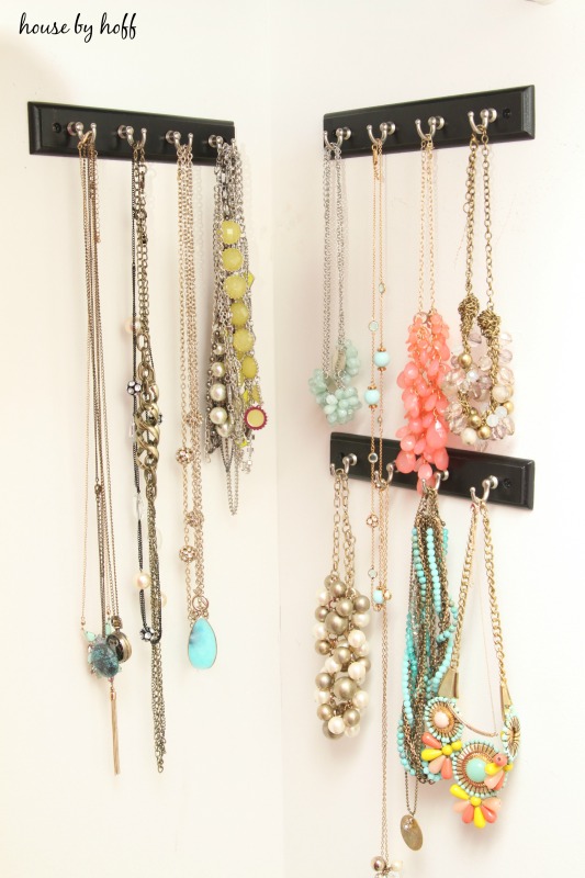 Multi colored necklaces hanging on hooks on the wall.