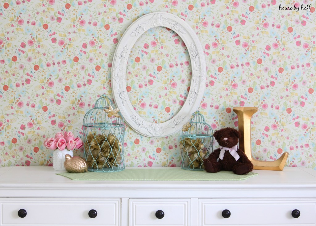 Vintage floral wall paper with white dresser in front of it.