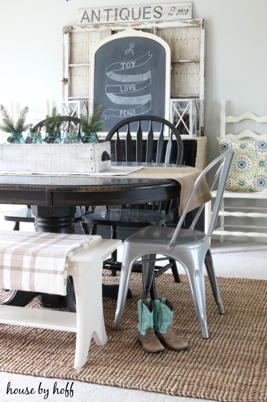 A dining room table with cowboy boots beside it.