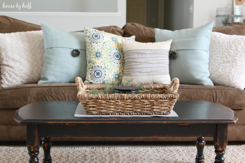 A dark wood coffee table with a wicker basket on top of it.