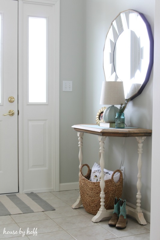 A large round mirror above the side table beside the front door.
