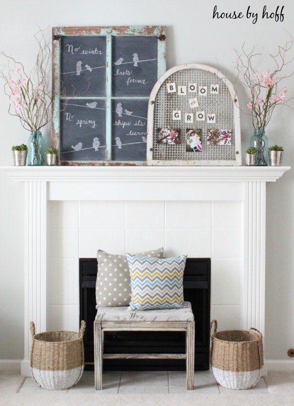 A white fireplace with a small bench in front of it and pillows on the bench.