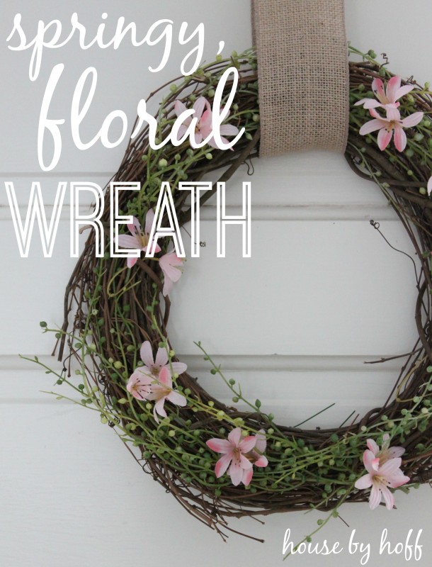 A pink and green floral wreath hanging on a door.