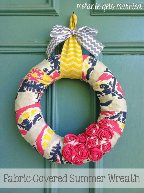 A wreath that is covered in fabric with tones of pink, yellow and grey.