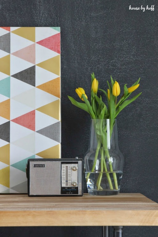 A radio and clear glass vase with yellow flowers in it on the desk.