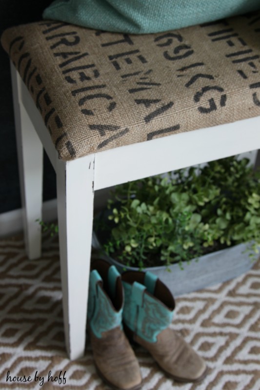 The white piano bench with a new fabric on it.