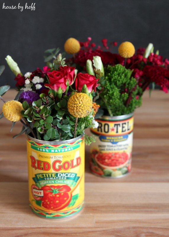 Two tin cans filled with flowers.