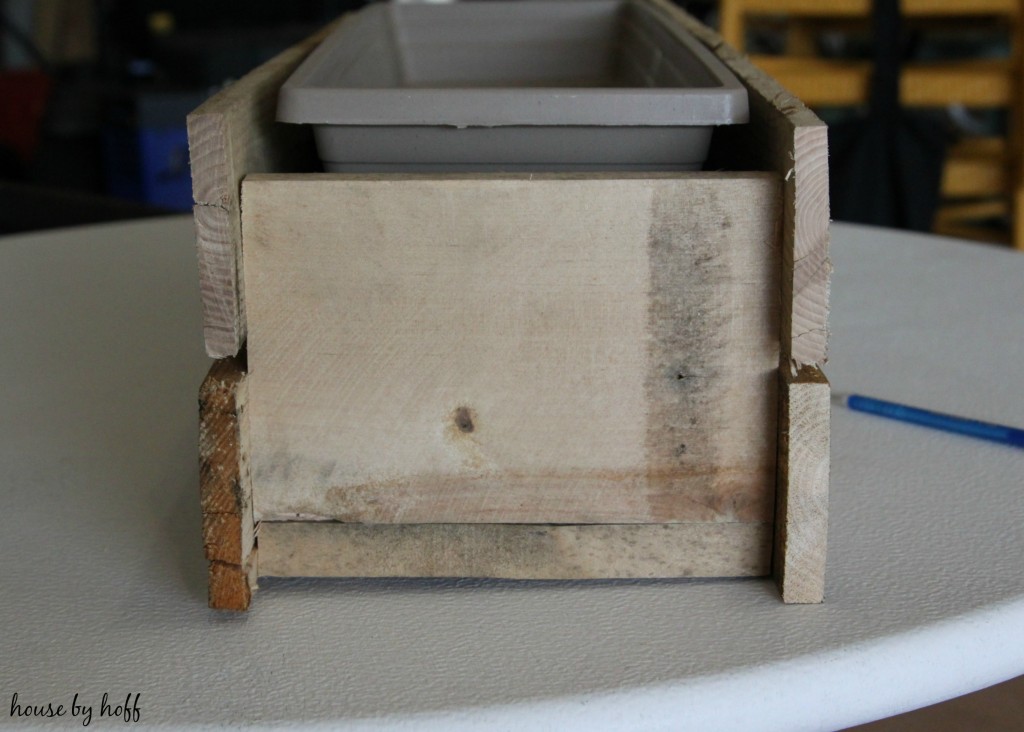 Putting the pallet wood around the plastic planter box.