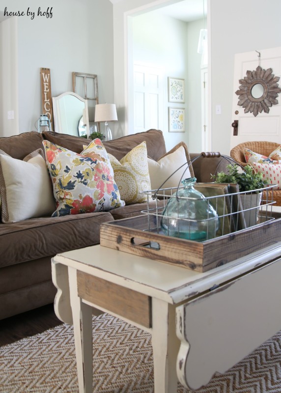 White coffee table in the living room with brown couch and throw pillows.