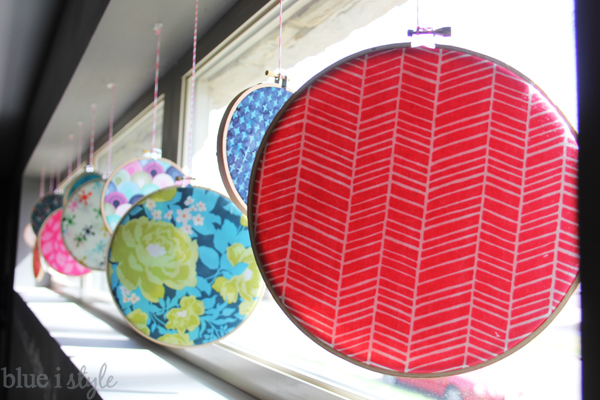 Red, blue and floral circle fabric art hanging in window.