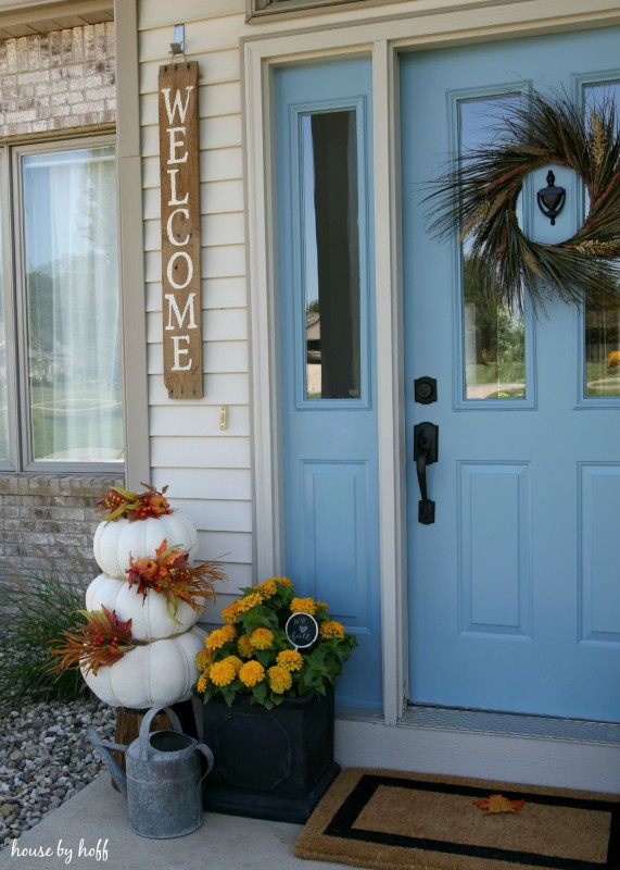 White pumpkins stacked on top of each other with autumn leaves decorating it.