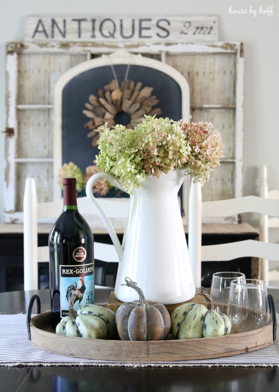 White vase on table with green and pink hydrangeas in it.