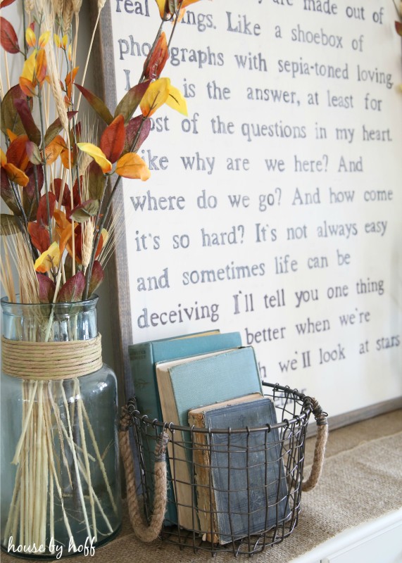 Clear glass vase with a hint of blue, and antique books beside the diy lyric sign.