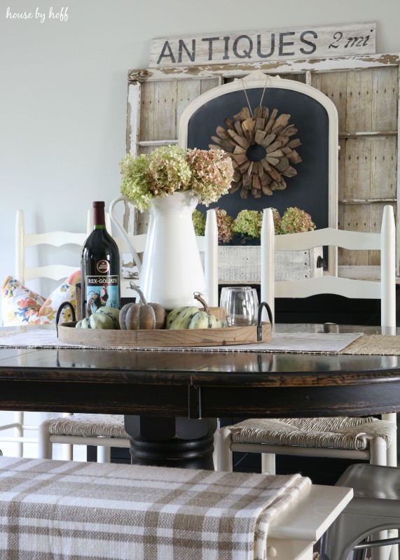 Wooden tray with pumpkins on them with a bottle of wine on the table.