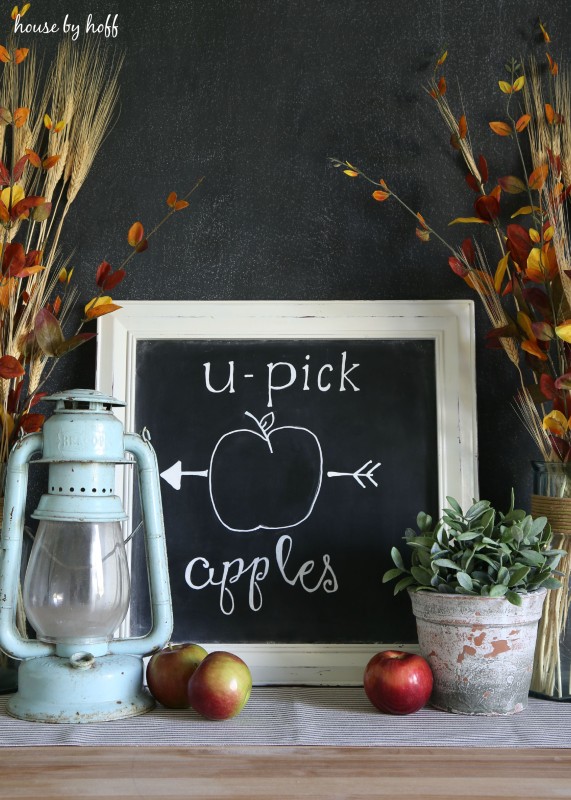 Chalkboard with lantern and plants on a desk.