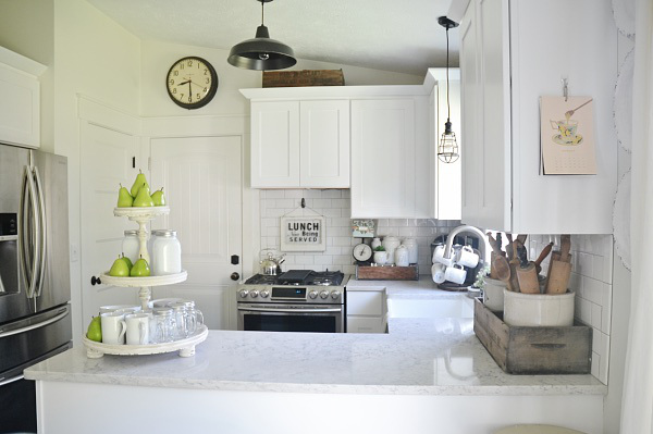 A white kitchen counter with a tiered tray and pears on the tray.