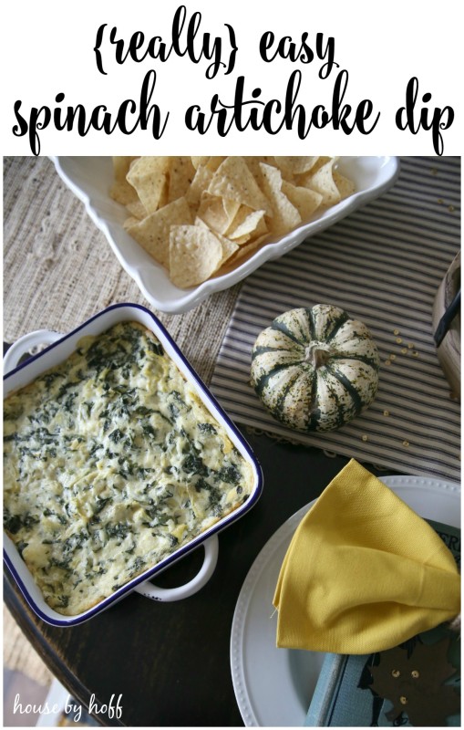 Spinach artichoke dip with mini pumpkins and chips on table.