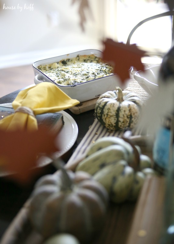 Mini pumpkins, yellow napkins, and autumn leaves on table.