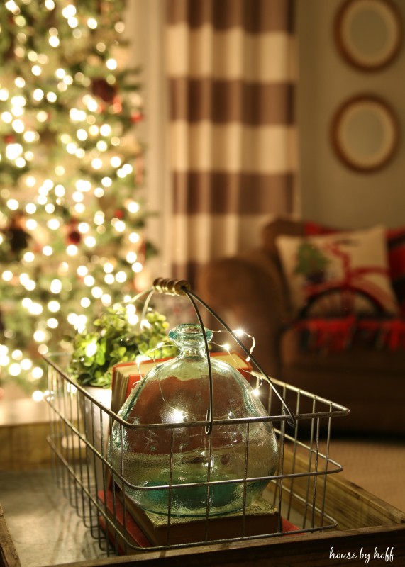 A metal wire basket with clear blue glass vase inside sitting on vintage books.