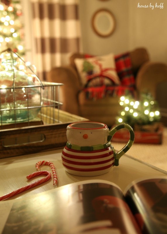 A snowman mug and candy canes on the table.