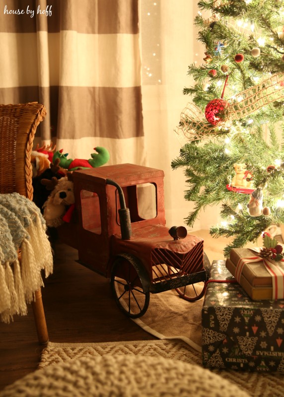 An antique looking toy truck is under the tree.