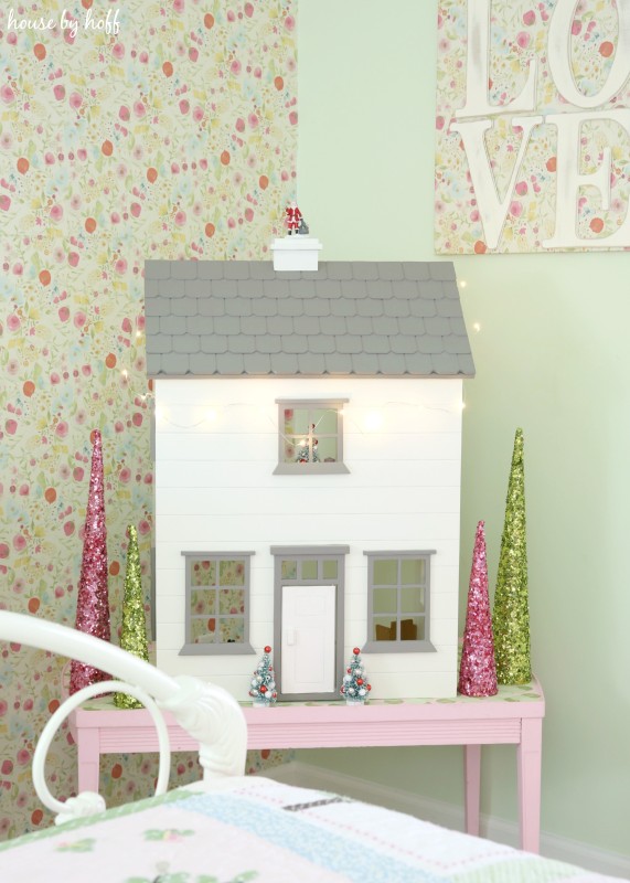 A white dollhouse with a gray room on a pink table in the bedroom.