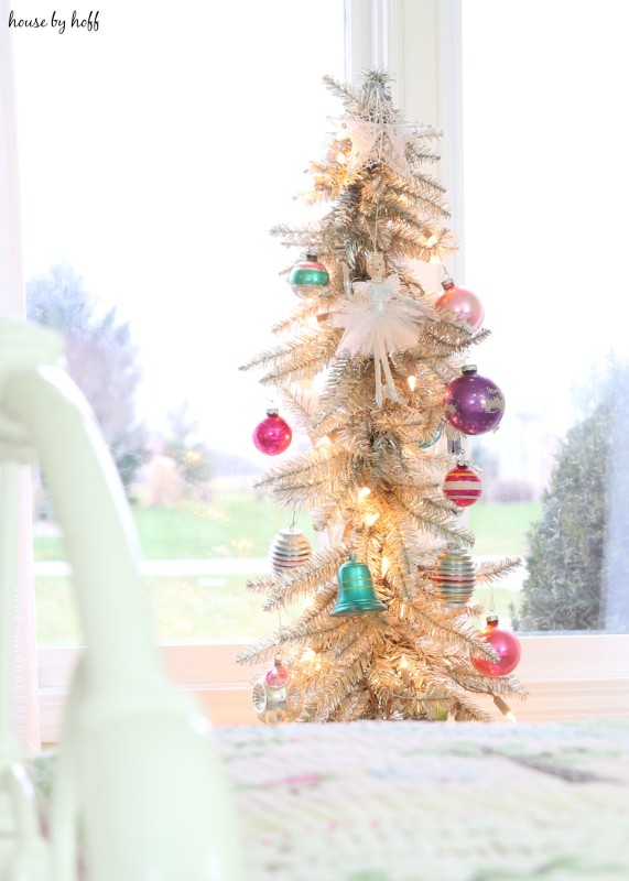 A decorated Christmas tree beside the bed in the little girl's room.