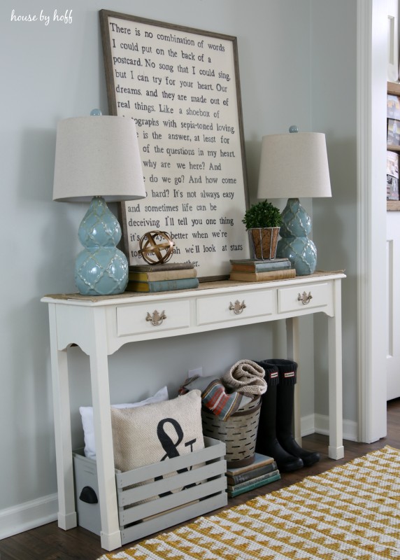 A white hallway table with a yellow and white rug in front of it.