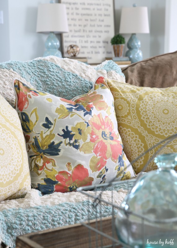 A red, blue and gold floral patterned pillow on the couch in the living room.