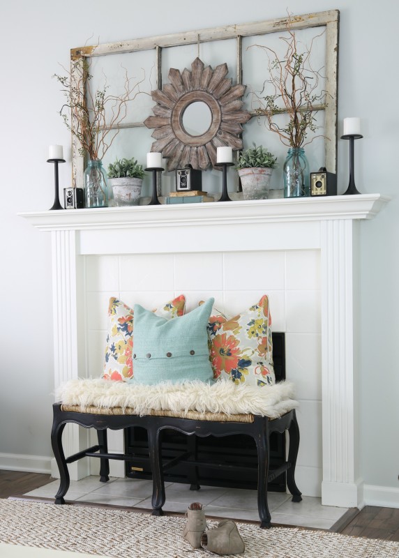 White fireplace with a bench in front of it, faux fur on the bench and pillows.