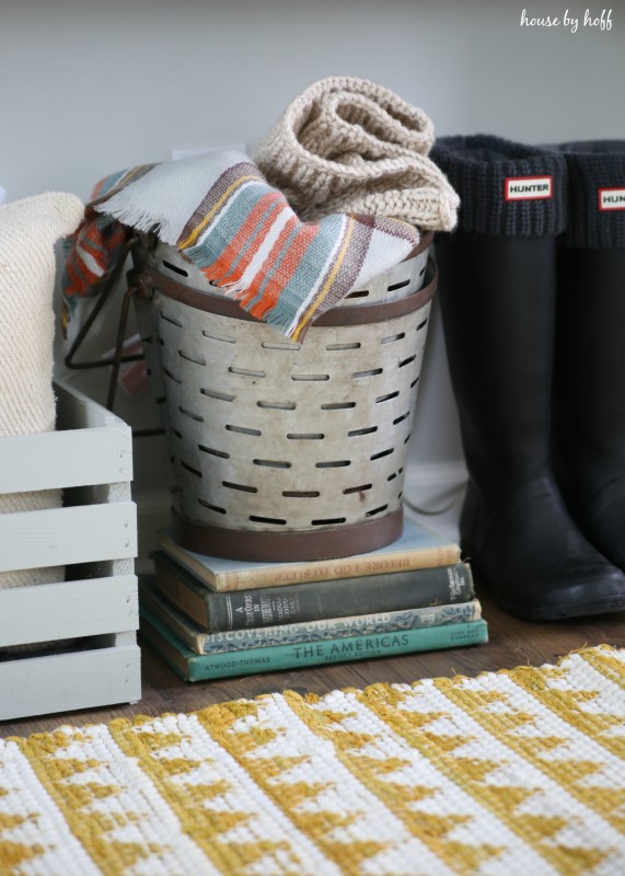 A basket full of blankets underneath the table, in hallway.