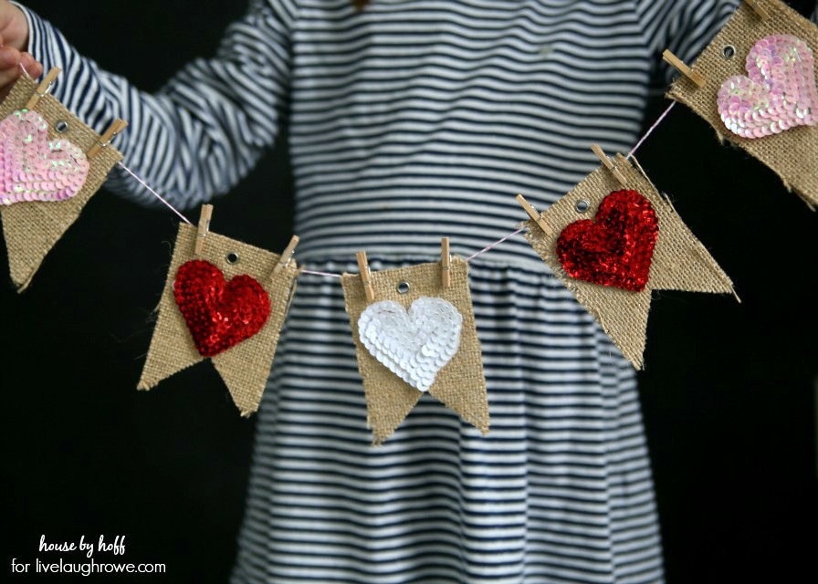 A small girl holding up a banner of hearts.