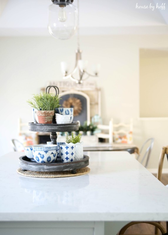 Blue and white bowls, cups and a small plant on the tiered tray in the dining room.