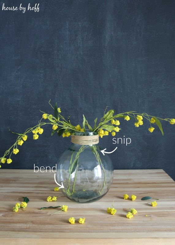 Snipping and bending the yellow flower stems into the vase.
