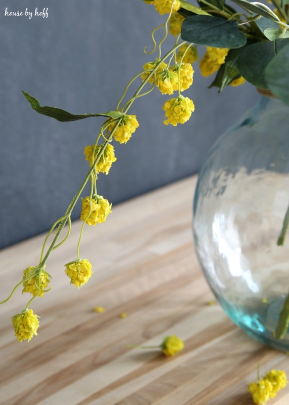 Vibrant yellow flowers trailing out of the centerpiece with some flowers falling off the stem.