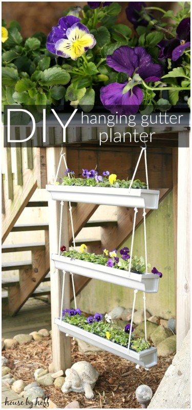 A hanging gutter planter with purple flowers in it.